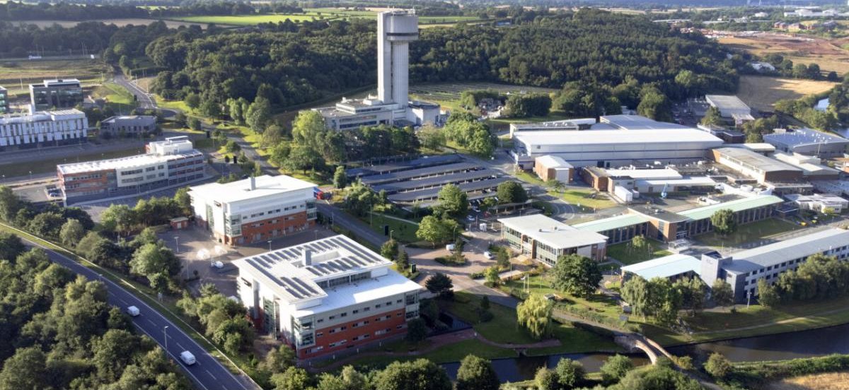 Aerial view of the Sci-Tech Daresbury campus, with the Daresbury Tower, laboratory buildings and surrounding woodland